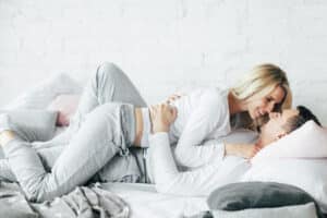 Happy middle aged couple kissing and cuddling in bed