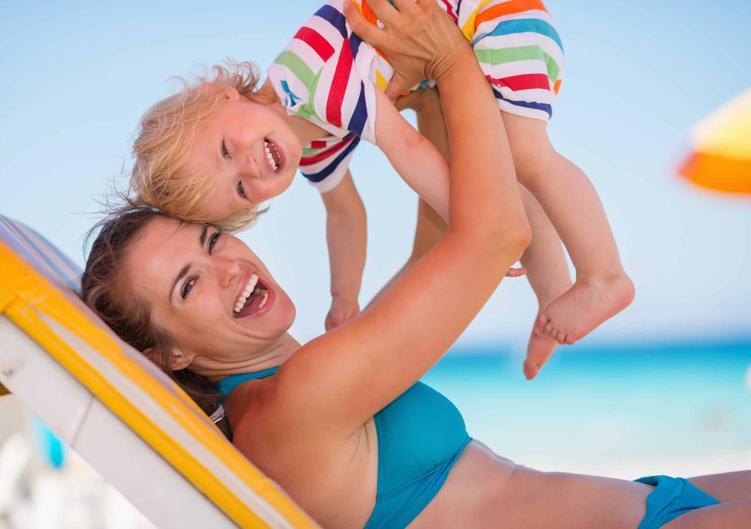 Portrait,Of,Mother,Playing,With,Baby,On,Beach